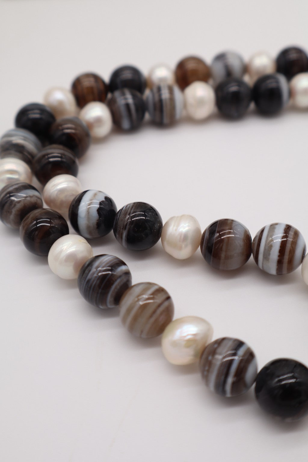 Dettaglio collana in agata fasciata e perle barocche, con venature naturali dell'agata e forme irregolari delle perle