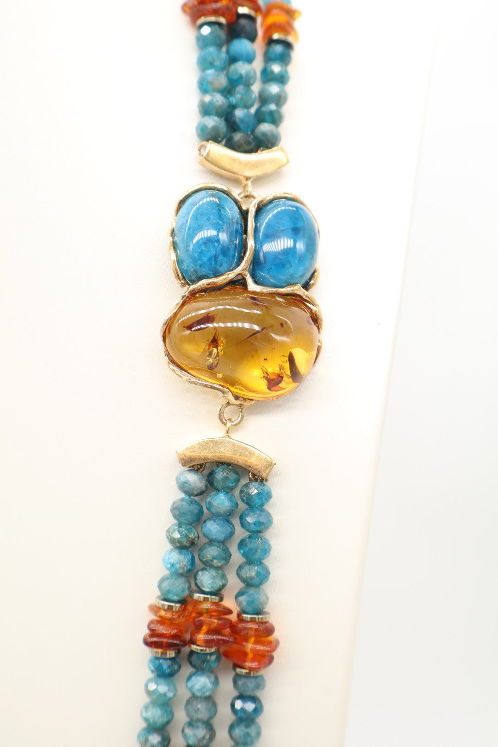 Dettaglio della grande ambra dorata centrale con due pietre di apatite blu