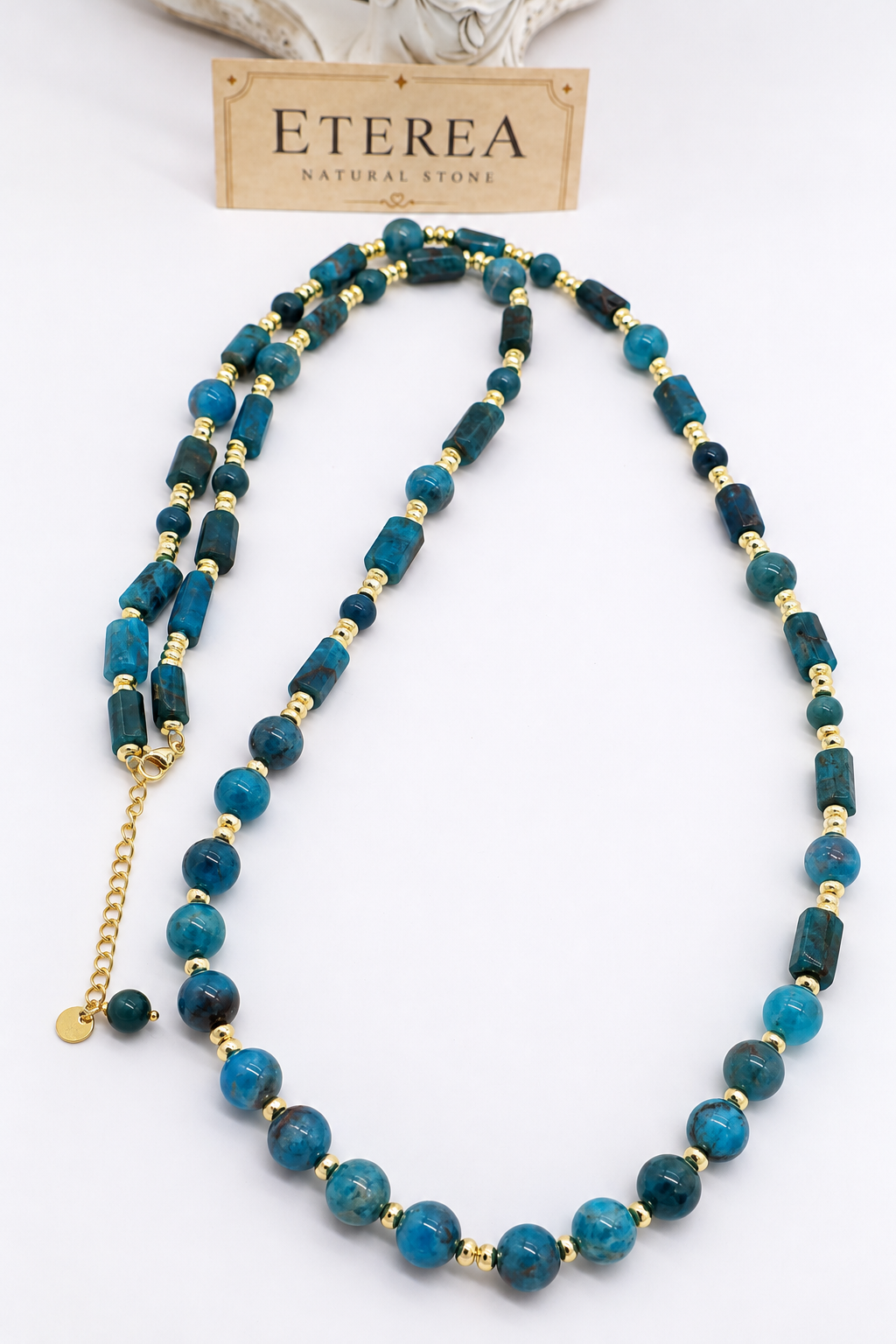 Collana lunga 80 cm in apatite blu naturale con sfere e cilindri, distanziatori in ematite dorata e chiusura in acciaio dorato – Eterea Natural Stone.
