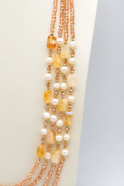 Collana multifilo da 90 cm con cinque fili di cristalli sfaccettati color champagne da 3 mm, citrino rettangolare da 14 × 10 mm, perle semi-round da 5 mm e distanziatori dorati.