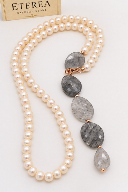 Collana lunga in perle di fiume e quarzo grigio sfaccettato con chiusura in argento rosé, indossata con abito color avorio.