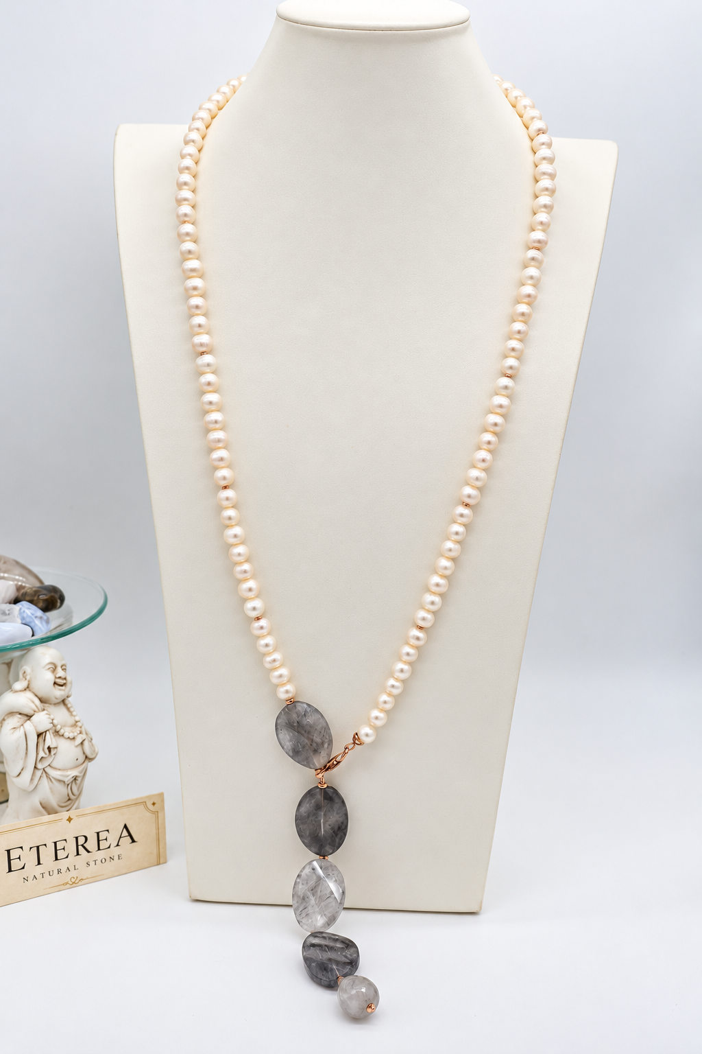 Collana lunga in perle di fiume e quarzo grigio sfaccettato con chiusura in argento rosé, indossata con abito color avorio.