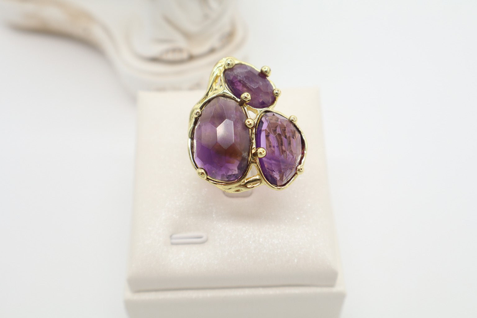 Anello cocktail in bronzo dorato con tre grandi ametiste naturali viola sfaccettate, design floreale e montatura scultorea.