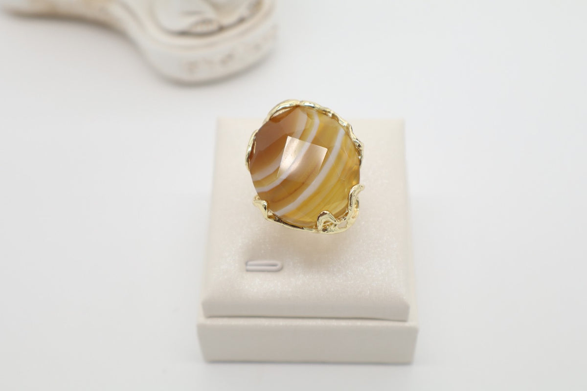 Anello cocktail in bronzo dorato galvanizzato con grande agata miele naturale sfaccettata e striature ambrate.