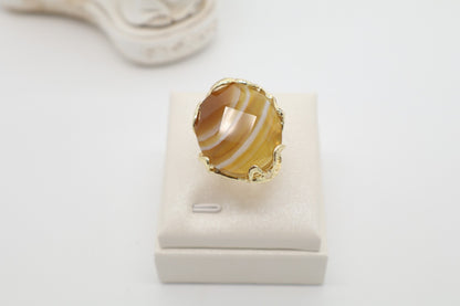 Anello cocktail in bronzo dorato galvanizzato con grande agata miele naturale sfaccettata e striature ambrate.
