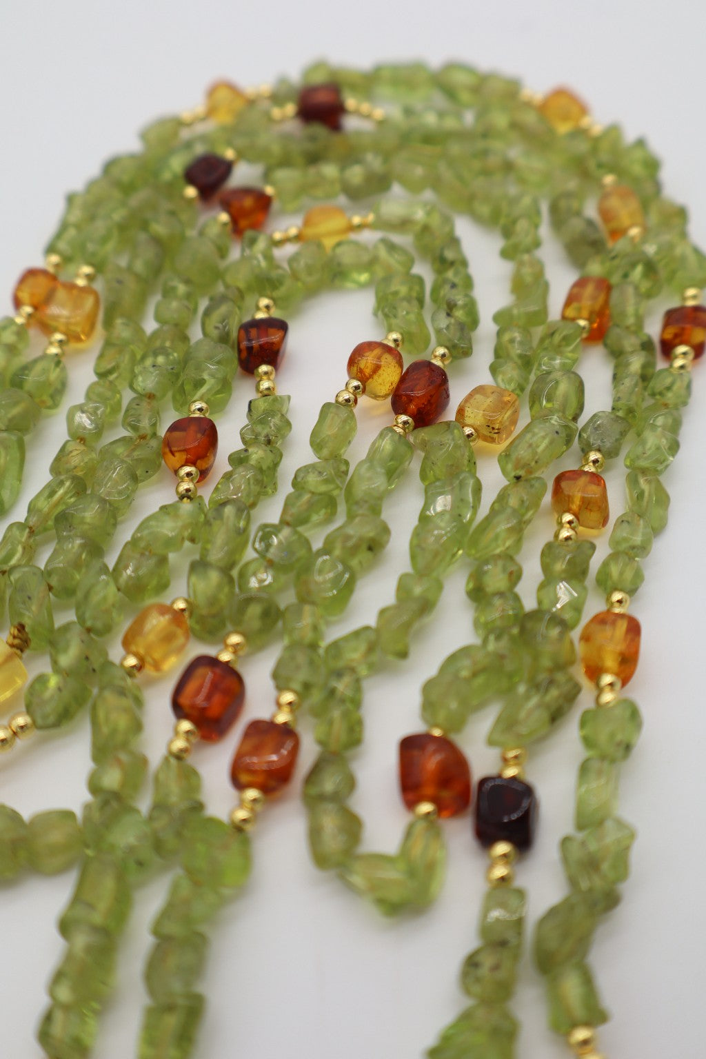 Dettaglio dei chips di peridoto naturale e degli elementi in ambra baltica della collana