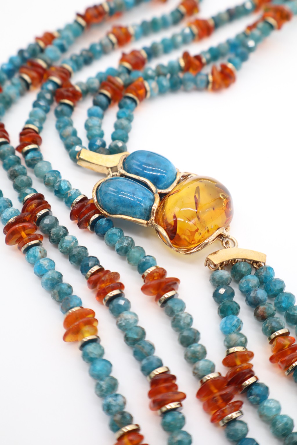 Dettaglio del centrale in ambra dorata e due pietre di apatite blu montato in struttura color oro