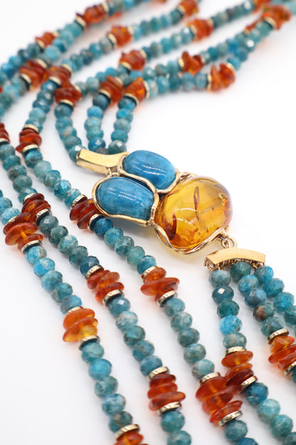 Dettaglio del centrale in ambra dorata e due pietre di apatite blu montato in struttura color oro