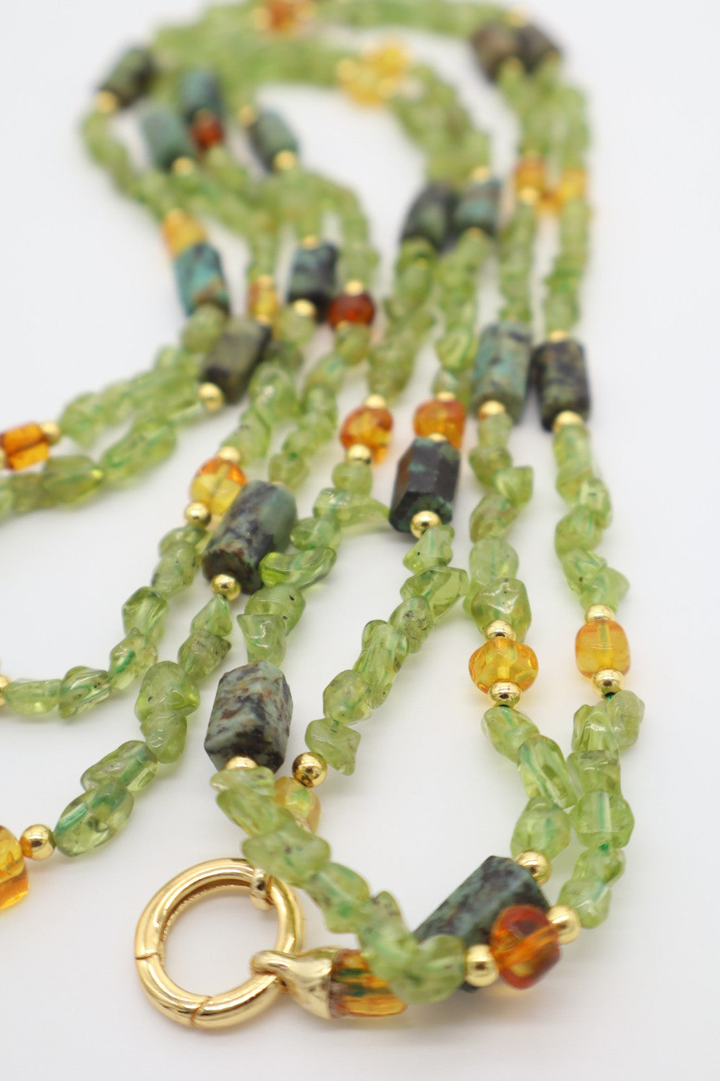 Dettaglio della collana in peridoto, ambra baltica e turchese africano con distanziatori dorati