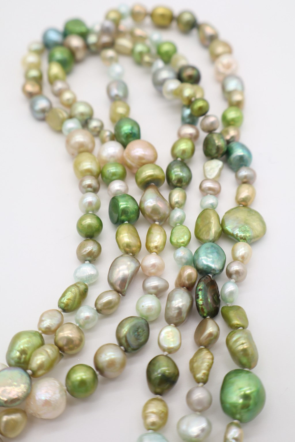 Dettaglio delle perle barocche verdi multicolore con forme irregolari e riflessi perlati
