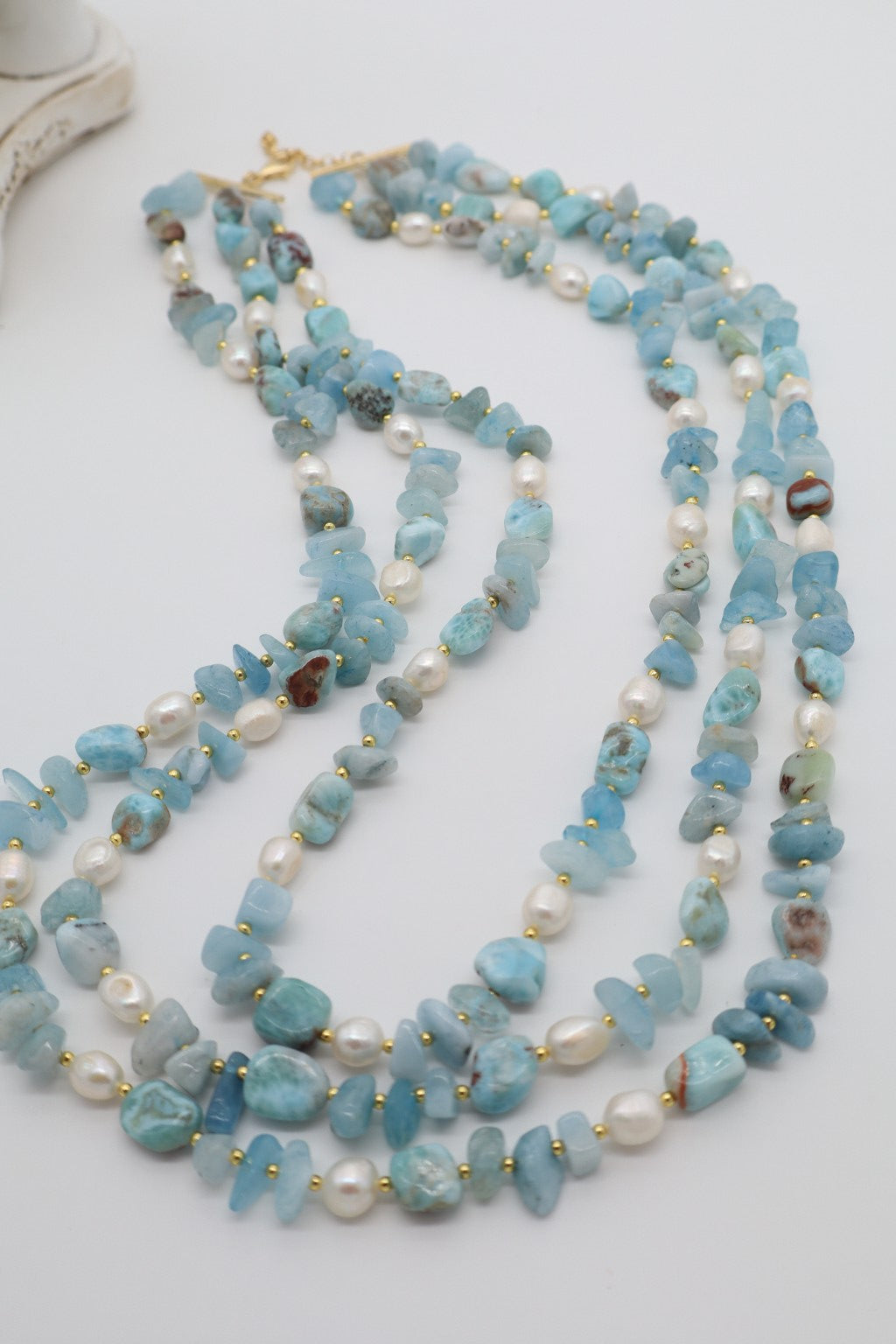 Dettaglio delle pietre naturali di acquamarina e larimar alternate a perle di fiume e distanziatori dorati.