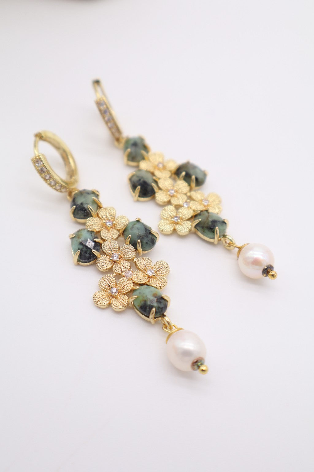 Dettaglio orecchini pendenti con Zoisite naturale sfaccettata, fiori dorati e perla