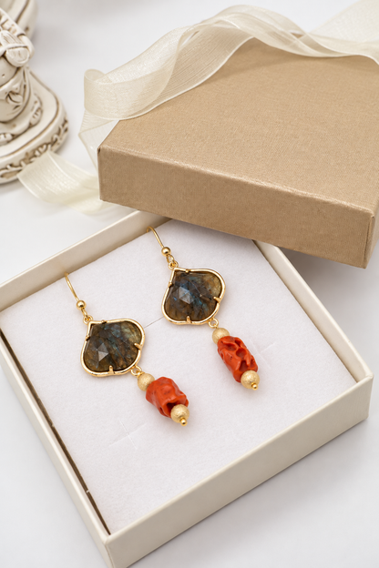 Orecchini pendenti in labradorite grigia e corallo mediterraneo presentati in una confezione regalo color avorio, con dettagli dorati e nastri chiari.