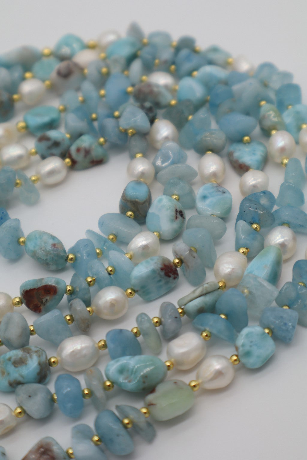 Particolare delle acquamarine e dei larimar dalla naturale varietà di tonalità, forme e inclusioni, abbinati a perle di fiume.