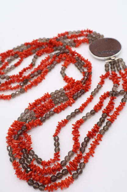 Particolare ravvicinato dei grani di corallo naturale e quarzo fumé della collana multifilo.