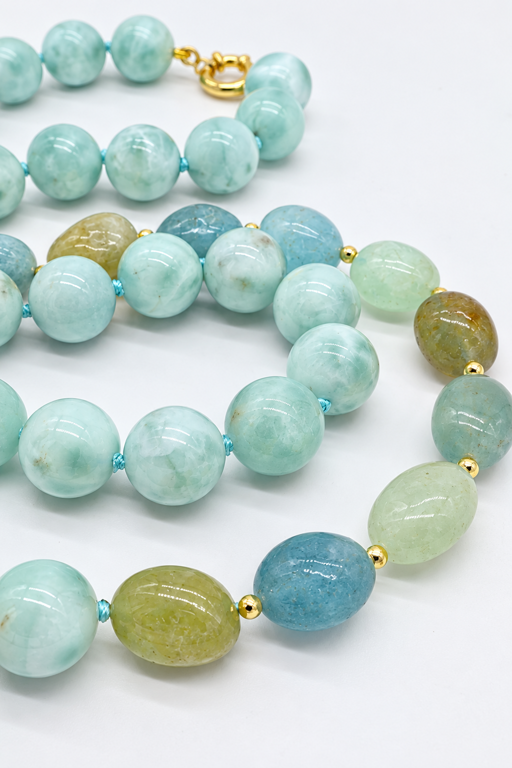 Collana Prestige in larimar e acquamarina con berillo naturale, sfere da 12 mm, pietre ovali irregolari, lavorazione annodata, chiusura in argento e lunghezza 70 cm.