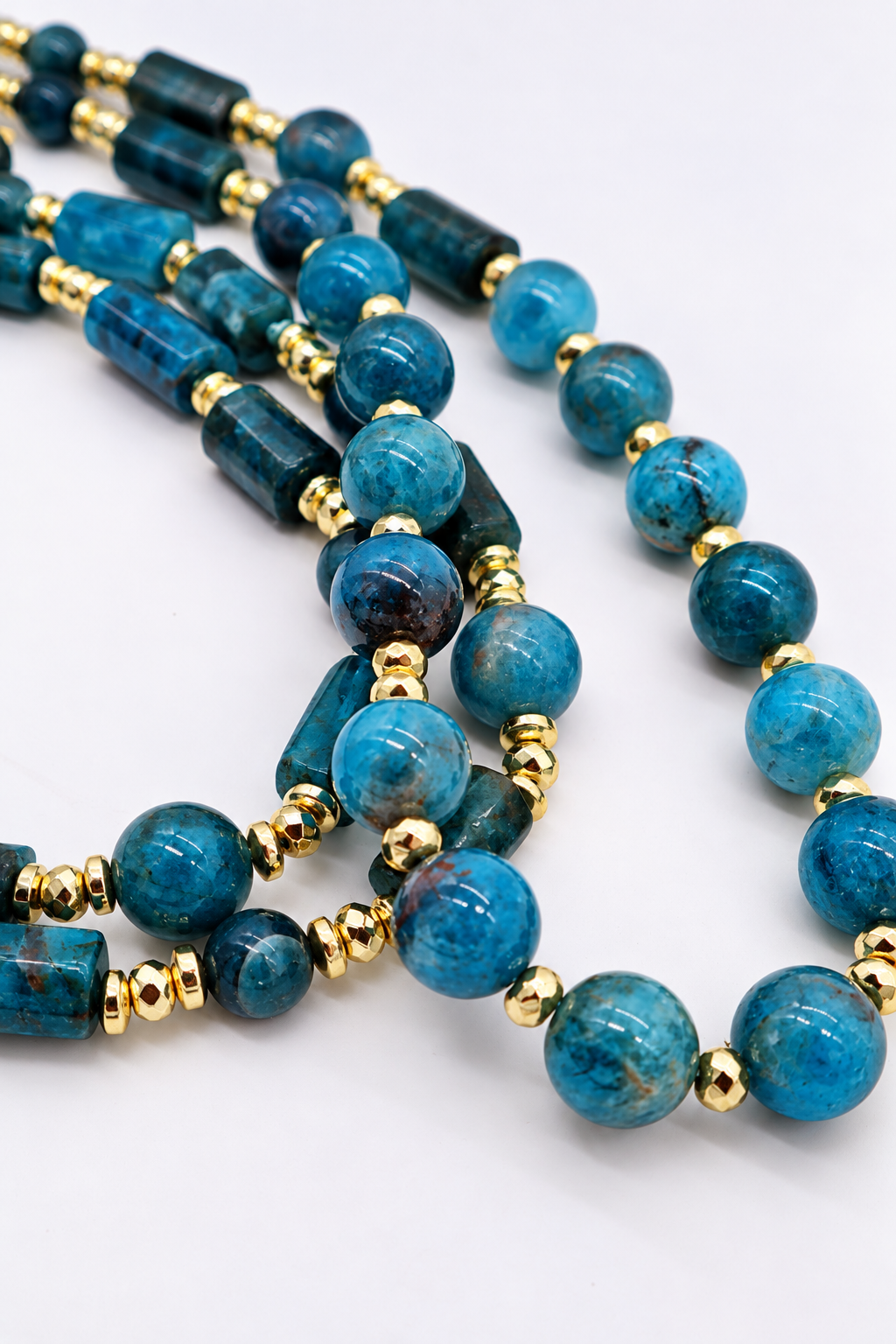 Collana lunga 80 cm in apatite blu naturale con sfere e cilindri, distanziatori in ematite dorata e chiusura in acciaio dorato – Eterea Natural Stone.
