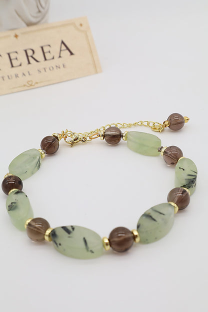 Bracciale in quarzo fumé e prehnite naturale con pietre ovali verde salvia, sfere trasparenti marroni e dettagli dorati, Eterea Natural Stone.